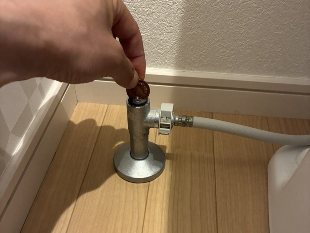 トイレの止水栓の溝に10円玉を当てる