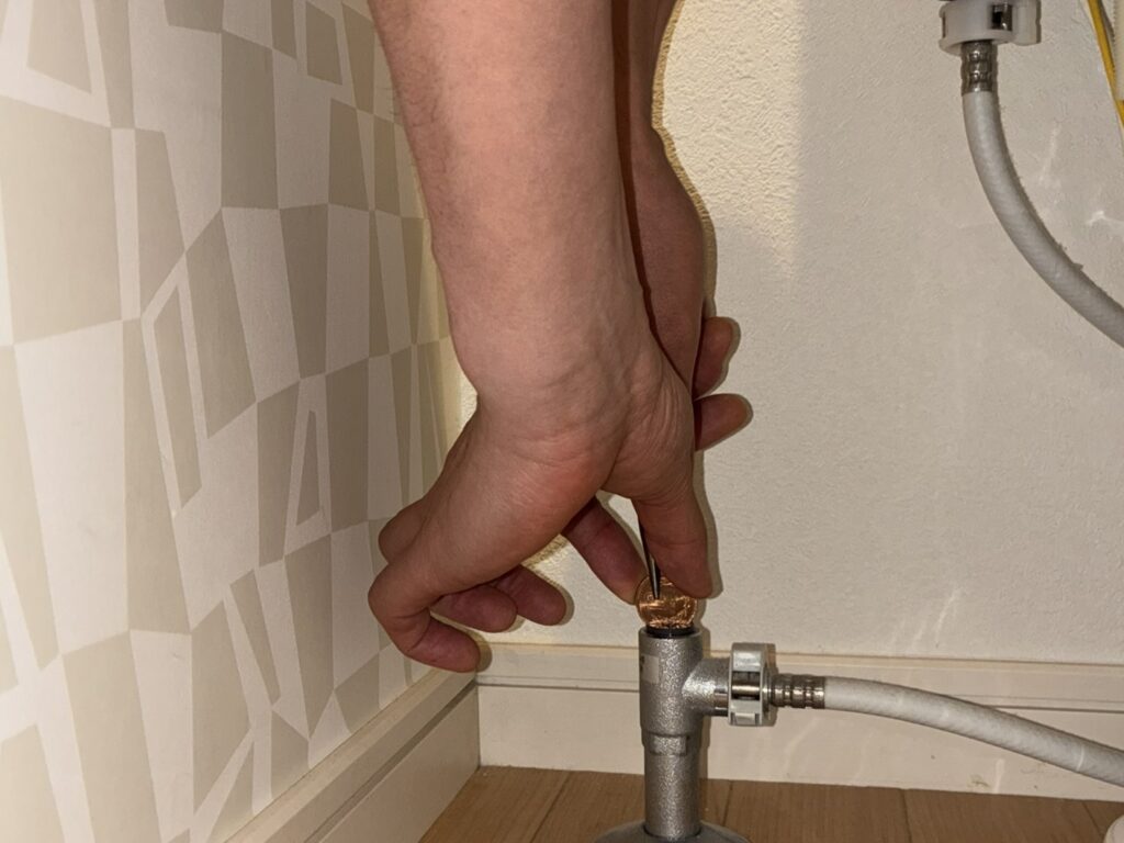 トイレの止水栓の溝に当てた10円玉をプライヤーで回す